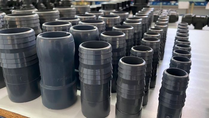 Spare PVC pipe parts neatly arranged in a line within a warehouse.