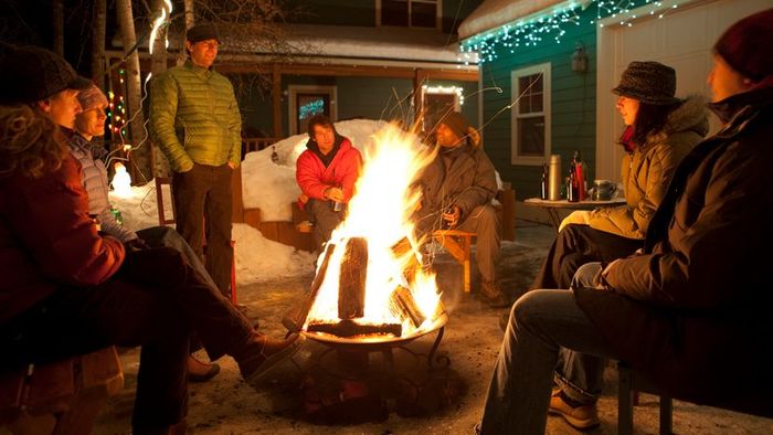 A group of friends gathered around a bonfire during the winter season.