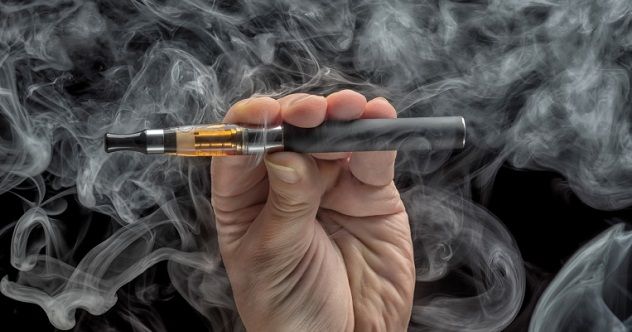 Hand holding an electronic cigarette against a dark backdrop