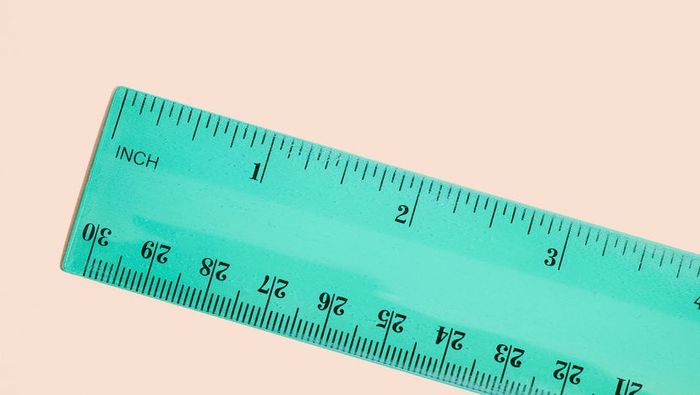 Top-down view of a green ruler placed on a peach-colored surface.