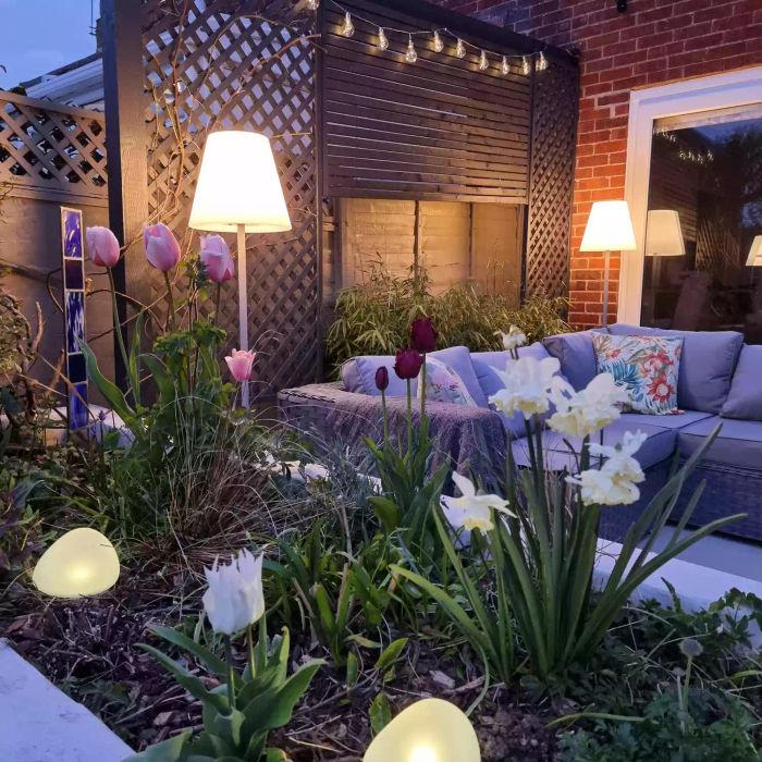 Outdoor lamps placed on a backyard patio beside a couch