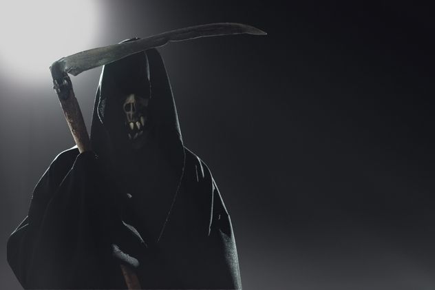 death with scythe standing in the dark