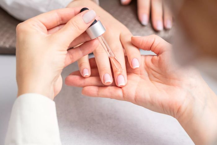 A person applying cuticle oil to their nails
