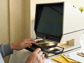 A person sitting at a table using a microfiche reader.