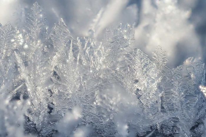 A close-up shot of translucent ice crystals appearing as frost on a surface.