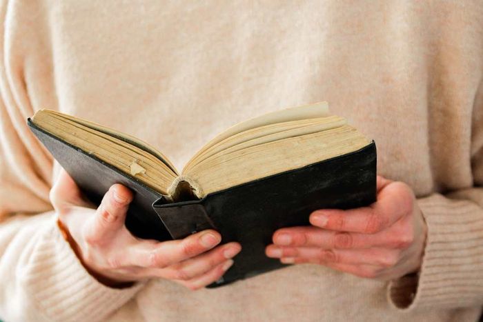 A pair of hands holding an open book.