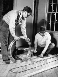 Two individuals working together to install a radiant floor heating system.