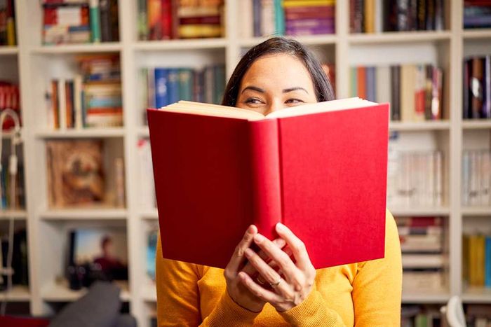 A woman holding a book in front of her face and laughing