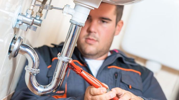 A plumber working on a sink drain