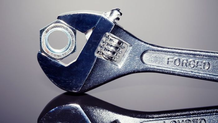 A wrench gripping a nut in its jaws.