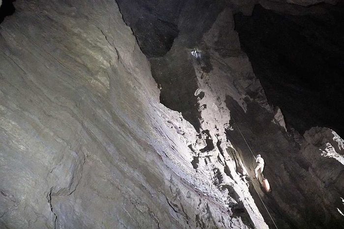 A caver ascends a vertical wall inside Veryovkina Cave.