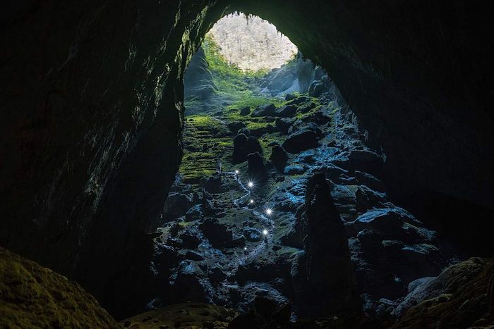 Hikers make their way up a steep trail toward a skylight in Son Doong cave.