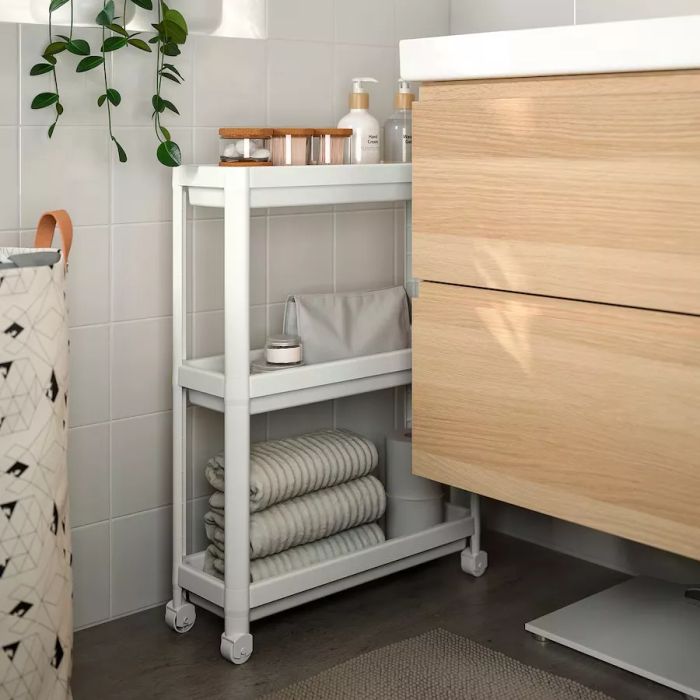For spaces with limited storage, consider adding a slim, rolling shelving unit that can fit between a vanity and toilet or beneath a pedestal sink. This clever solution offers extra space for essentials like lotions, makeup, or hair care products. For small items, such as cotton balls or makeup remover pads, store them in tall, clear containers to keep them organized and mess-free.