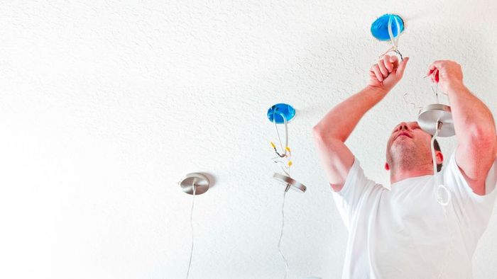 An electrician installing ceiling fixtures.