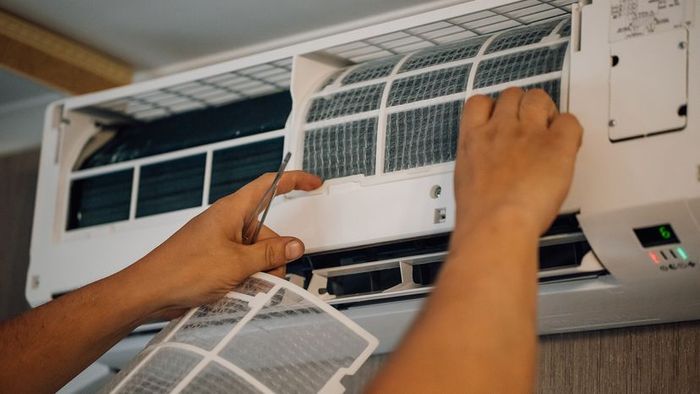 A person replacing the filter on an air conditioning unit