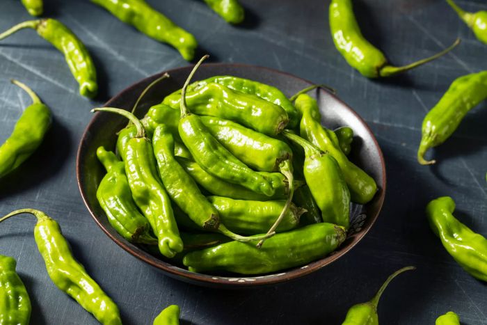 A bowl of shishito peppers on a counter