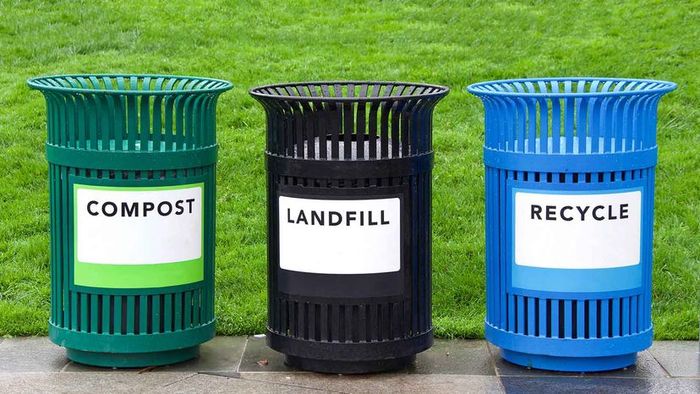 A green compost bin, a black bin labeled ‘landfill,’ and a blue recycling bin are shown from left to right.