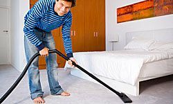 person vacuuming beneath a bed