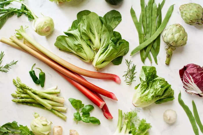 A collection of spring vegetables arranged on a marble countertop