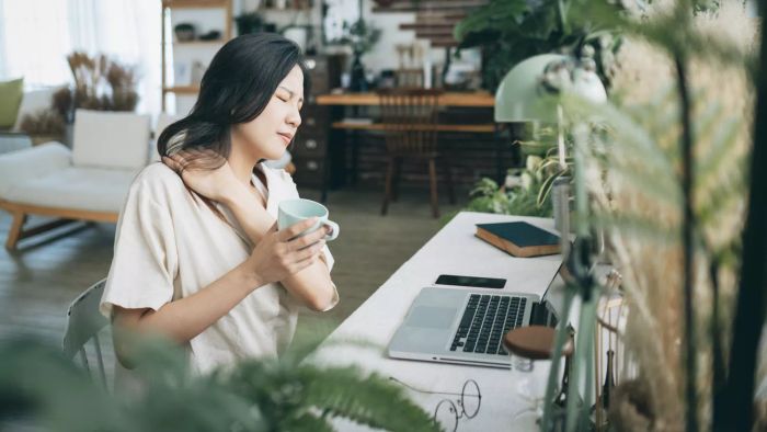 How to Ease Tension in the Face, Neck, and Jaw: Asian woman struggling with using a laptop at home
