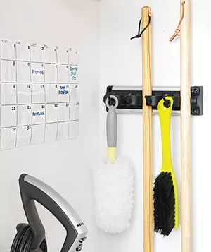 Wall calendar and brooms hanging in a utility closet