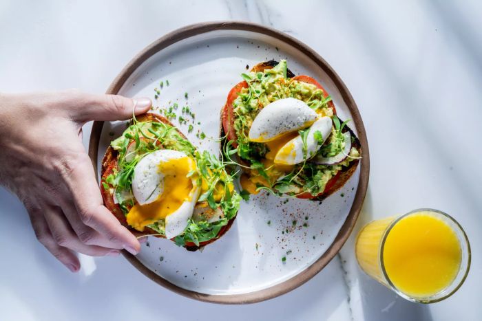 Two slices of avocado toast topped with sprouts and a Yo Egg split open to reveal its yolk.
