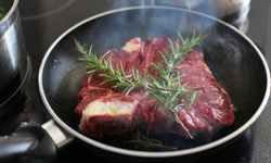 A piece of meat cooking in a pan with a garnish on top.