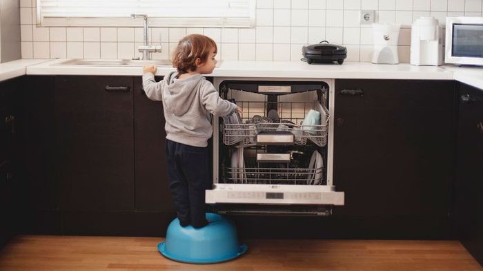 A child loading a dishwasher