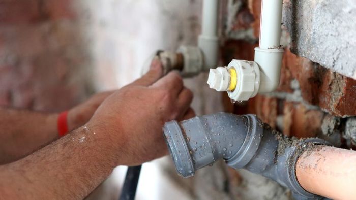A plumber repairing a broken pipe.