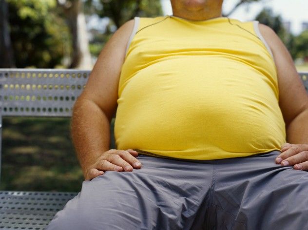 A side view of a man sitting on a bench in a park