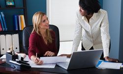A woman and her lawyer reviewing documents in an office setting.