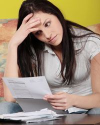 A woman looking frustrated while staring at her bills