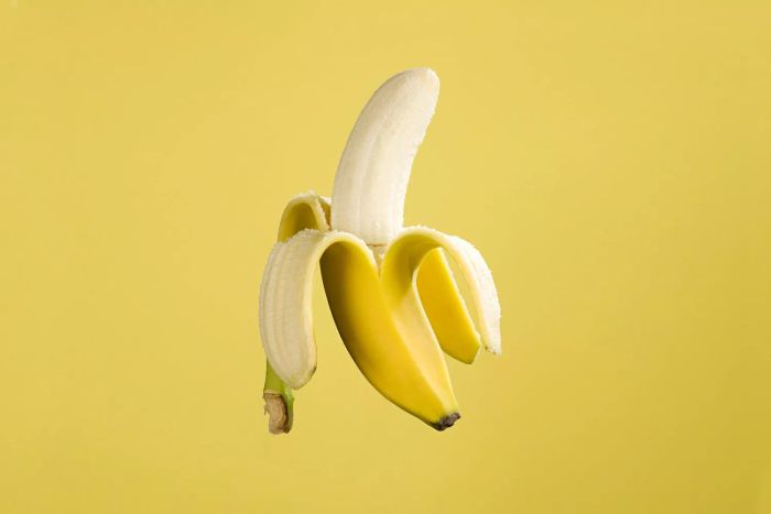 Half-Peeled Banana on a Bright Yellow Background
