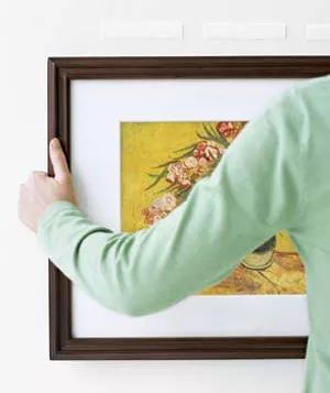 Woman using velcro to hang a picture