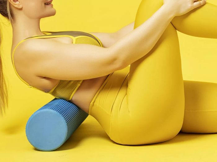 How to Relieve Muscle Soreness: Woman using a foam roller to relax her back.