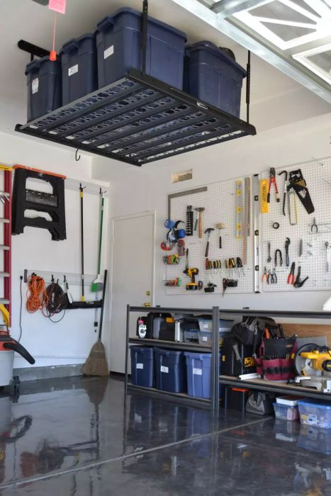 Overhead Storage with Blue Bins Near the Ceiling, White Pegboard with Organized Tools in Garage