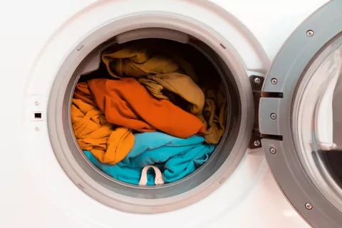 Close-up of a washing machine with the door open, showcasing brightly colored clothes inside.