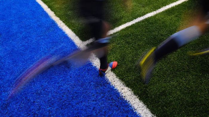 A rugby game taking place on an artificial turf field.