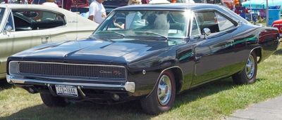 The 1968 Dodge Charger R/T was a head-turner, with its sleek, sculpted 'coke-bottle' body and menacing blacked-out grille with hidden headlights. The 'R/T' designation meant it was a performance-oriented machine, ready for both the streets and the drag strip. Powered by a 375-horsepower 440 Magnum V8, the Charger R/T could complete the quarter-mile in just under 15 seconds, with a price of around $3,500. For a more powerful option, buyers could choose the Hemi engine, though only 475 Hemi R/T Chargers were produced. This engine upgrade added $600 to the price and shaved the quarter-mile time to the mid-13-second range. A total of 96,100 Chargers were made in 1968, with 17,000 of those being R/T models. The Charger R/T was immortalized in popular culture, thanks to its appearance in *Bullitt*, where the car played a pivotal role in one of the most iconic car chases in film history, with Steve McQueen's nemesis driving the black 440 Magnum R/T.