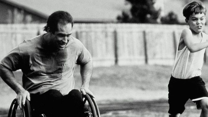 A black-and-white photo showing a man in a wheelchair racing his son on a track