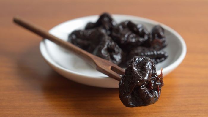 Dried plums resting on a plate.