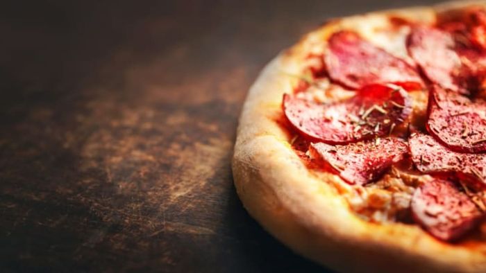 A pizza sitting on a wooden table.