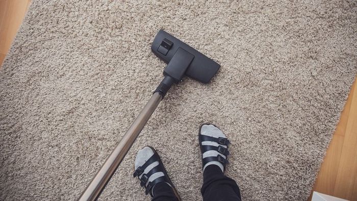 A top-down view of someone vacuuming a gray carpet