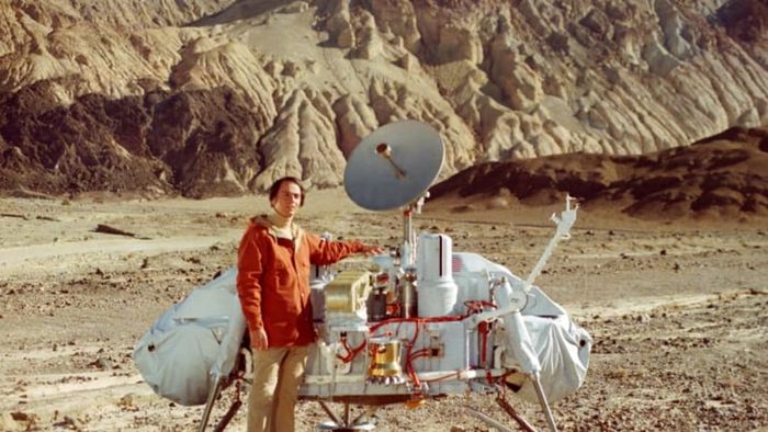 Carl Sagan standing alongside a model of the Viking Lander.