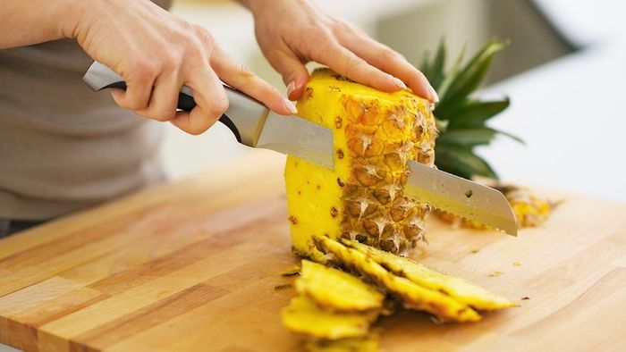 someone slicing a pineapple
