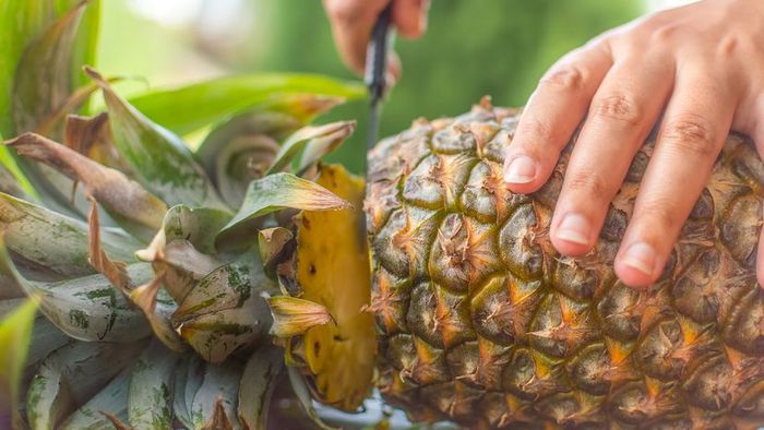 someone slicing a pineapple