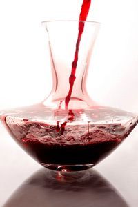 Pouring red wine into a glass decanter for aeration
