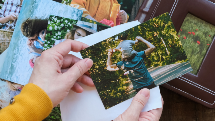 A pair of hands holding a stack of small four-by-six printed photos