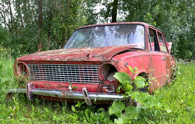 An old, abandoned car in a meadow