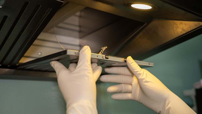 individual wearing gloves cleaning a range hood